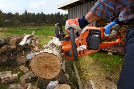 Homme tronçonnant une bûche avec une machine à batterie